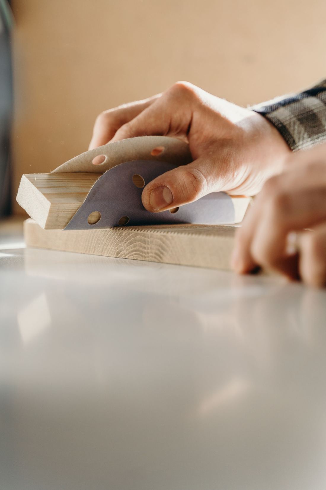 Hands sanding a small block of wood.